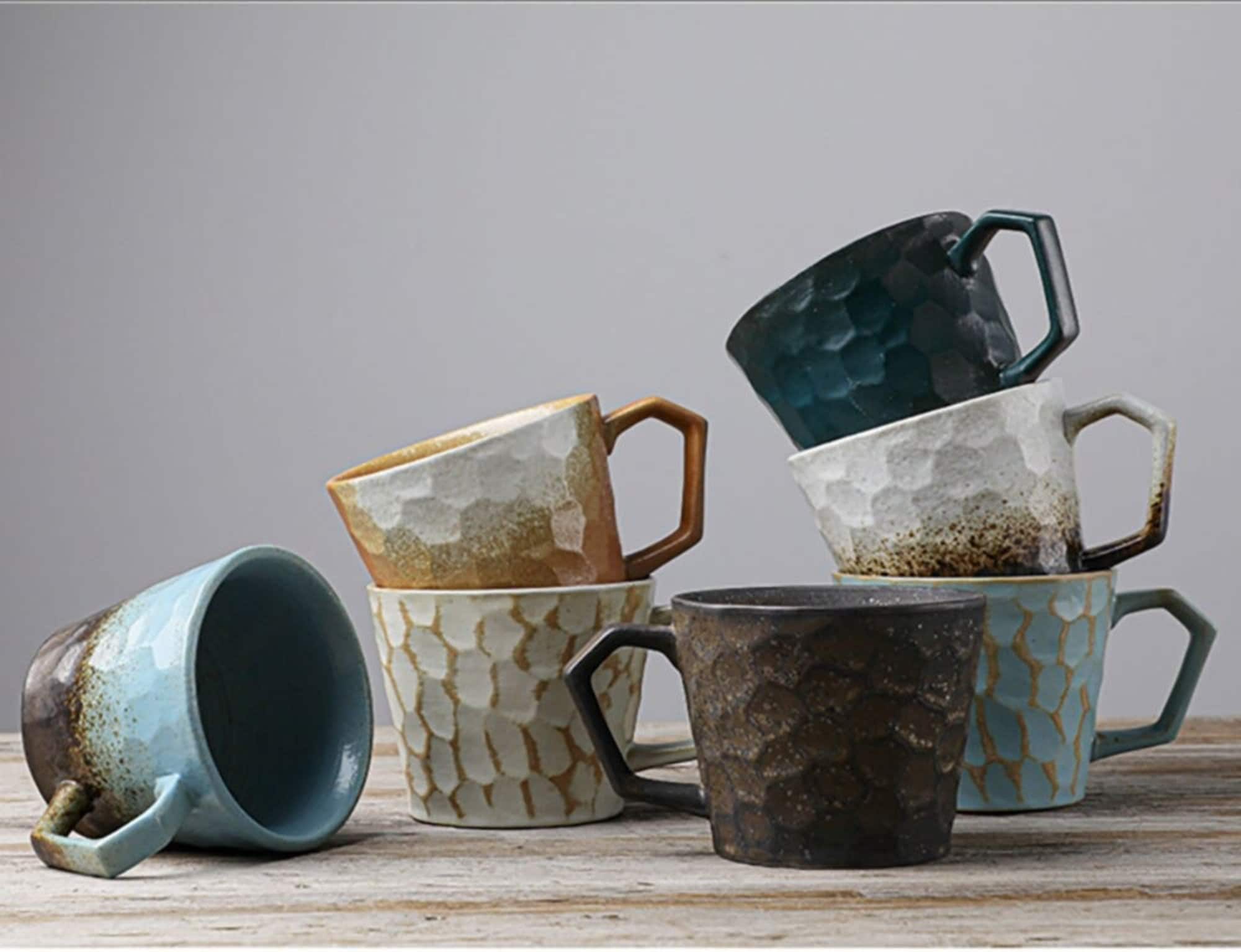 Stoneware coffee cup vintage Japanese style mug in blue, brown, white, and teal hues on a wooden surface.